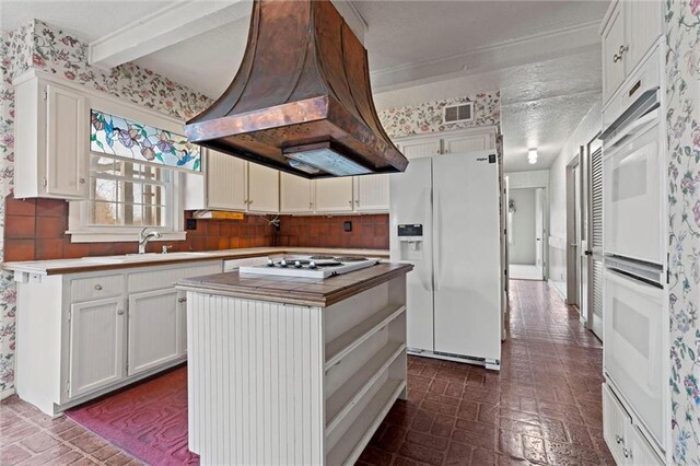 kitchen with white cabinetry, white appliances, a center island, and custom exhaust hood