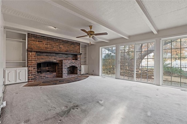 unfurnished living room with ceiling fan, carpet, a fireplace, a textured ceiling, and beamed ceiling