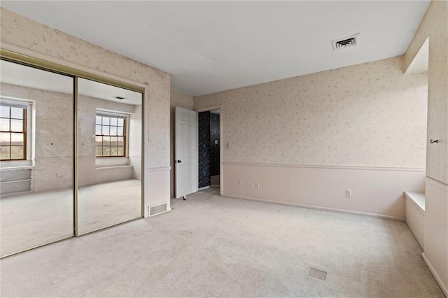 unfurnished bedroom featuring a closet and light colored carpet