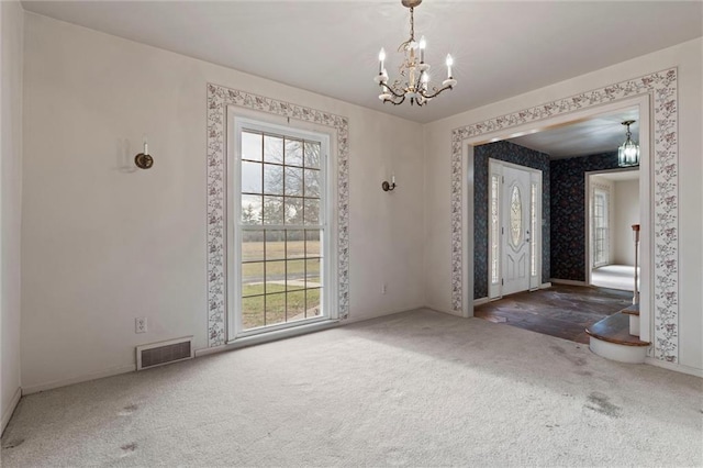 unfurnished room featuring an inviting chandelier and dark colored carpet