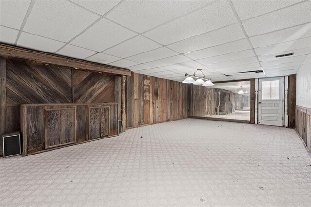 basement with a drop ceiling and wooden walls