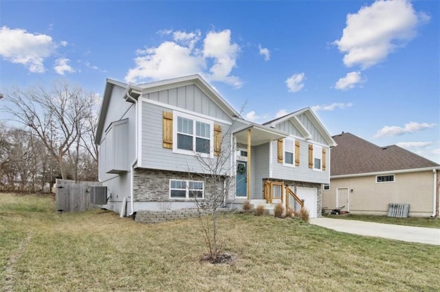 bi-level home featuring central air condition unit, concrete driveway, board and batten siding, stone siding, and a front lawn