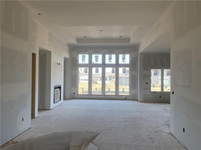 unfurnished living room featuring a tray ceiling and a high ceiling