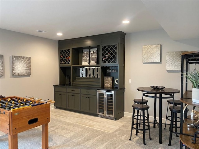interior space with a sink, beverage cooler, baseboards, recessed lighting, and indoor wet bar