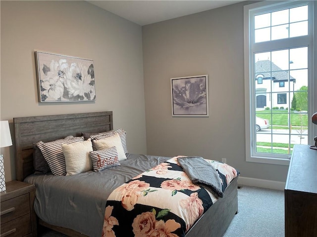 carpeted bedroom featuring baseboards and multiple windows