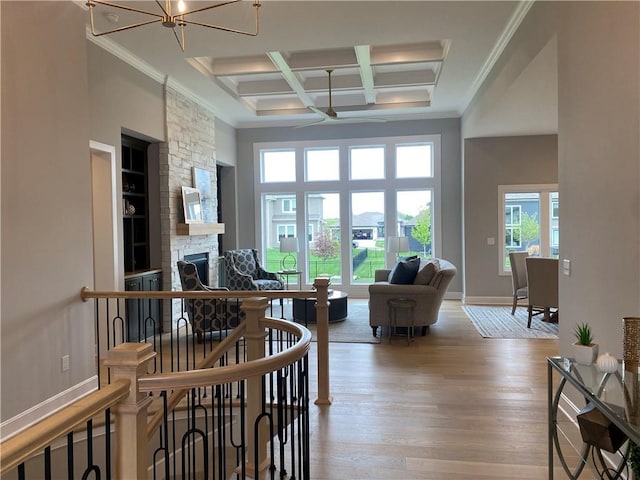 living room featuring wood finished floors, an inviting chandelier, coffered ceiling, a stone fireplace, and beam ceiling