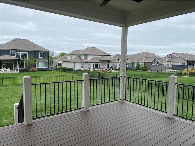 deck featuring a lawn, fence, ceiling fan, and a residential view