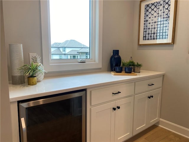bar featuring wood finished floors, wine cooler, and baseboards