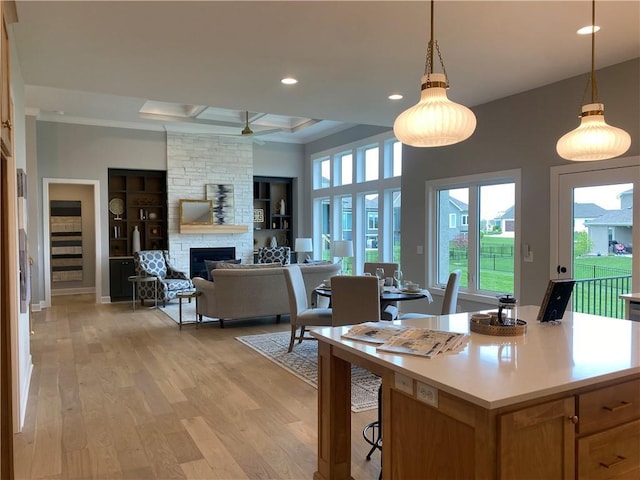 kitchen with recessed lighting, light wood-style flooring, decorative light fixtures, light countertops, and a fireplace