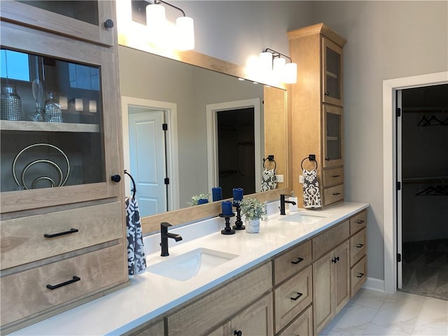 bathroom with a spacious closet, marble finish floor, double vanity, and a sink