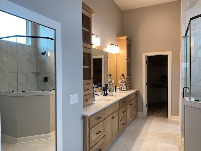 bathroom with a stall shower, a spacious closet, marble finish floor, and a sink