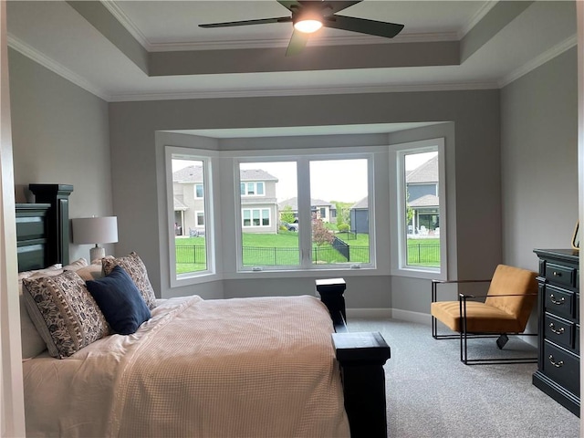 carpeted bedroom with baseboards, multiple windows, crown molding, and a tray ceiling
