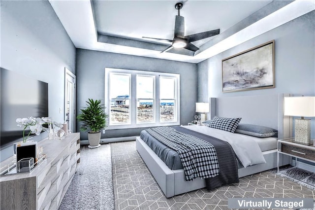 carpeted bedroom with ceiling fan and a raised ceiling