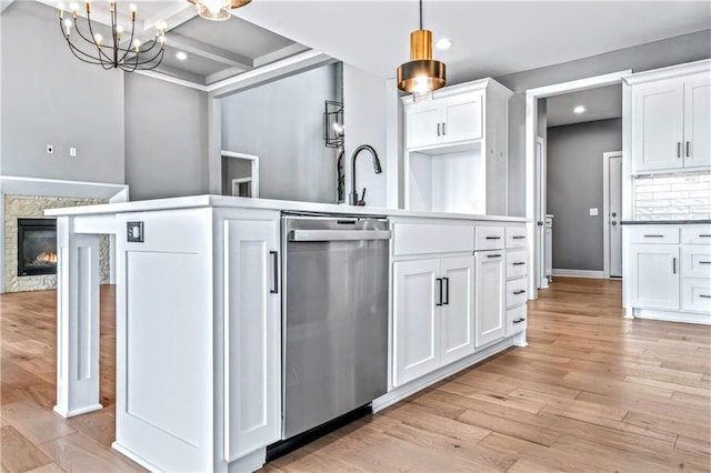 kitchen featuring stainless steel dishwasher, white cabinetry, and hanging light fixtures