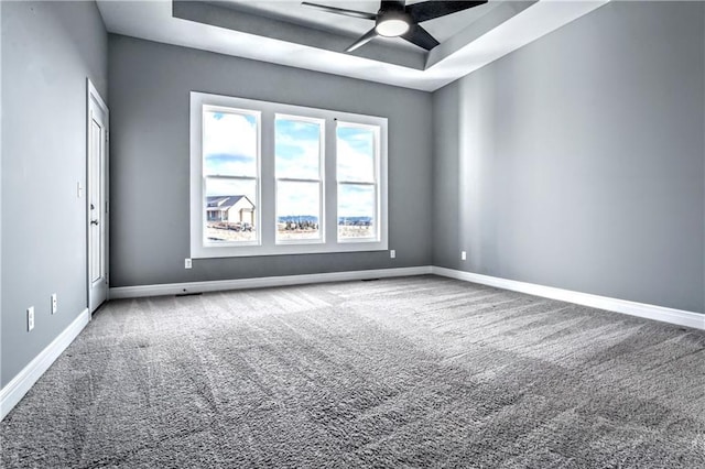 carpeted empty room with ceiling fan and a raised ceiling