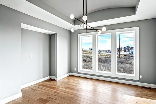 unfurnished dining area featuring light wood-type flooring and a notable chandelier