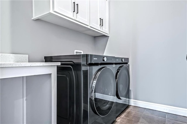 washroom featuring cabinets, independent washer and dryer, and dark tile patterned flooring