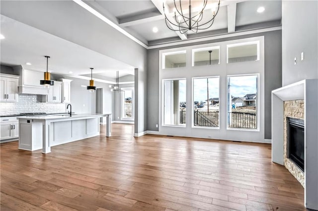 living room featuring beam ceiling, light hardwood / wood-style floors, a fireplace, and coffered ceiling