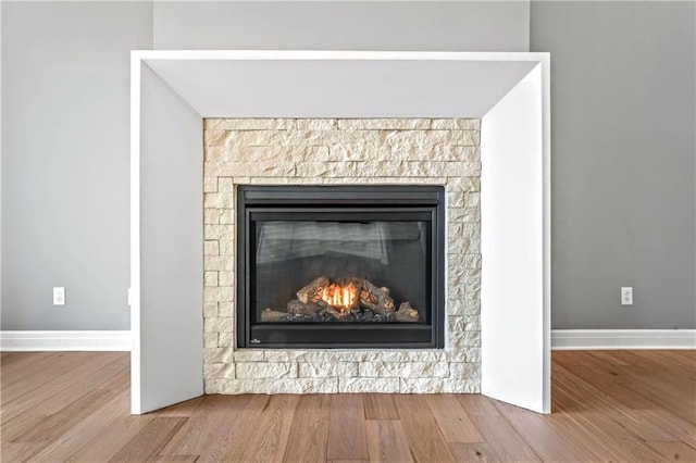 details with hardwood / wood-style flooring and a stone fireplace