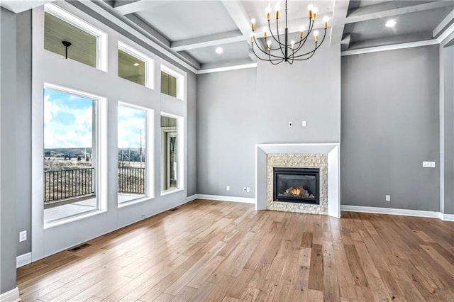 unfurnished living room featuring beam ceiling, light wood-type flooring, an inviting chandelier, and coffered ceiling