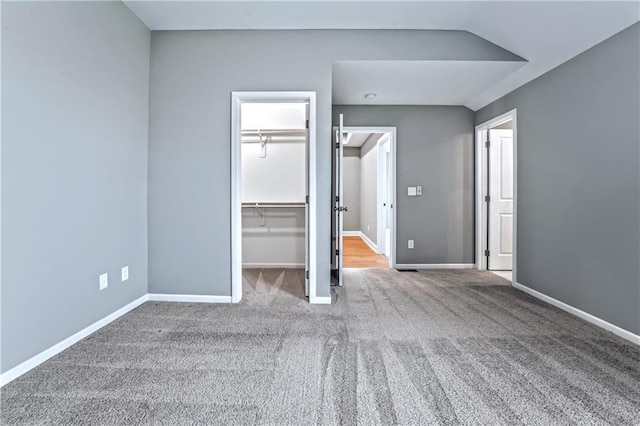 unfurnished bedroom featuring carpet, a walk in closet, and a closet