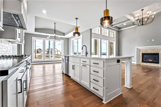 kitchen featuring white cabinetry, an island with sink, a chandelier, decorative light fixtures, and appliances with stainless steel finishes