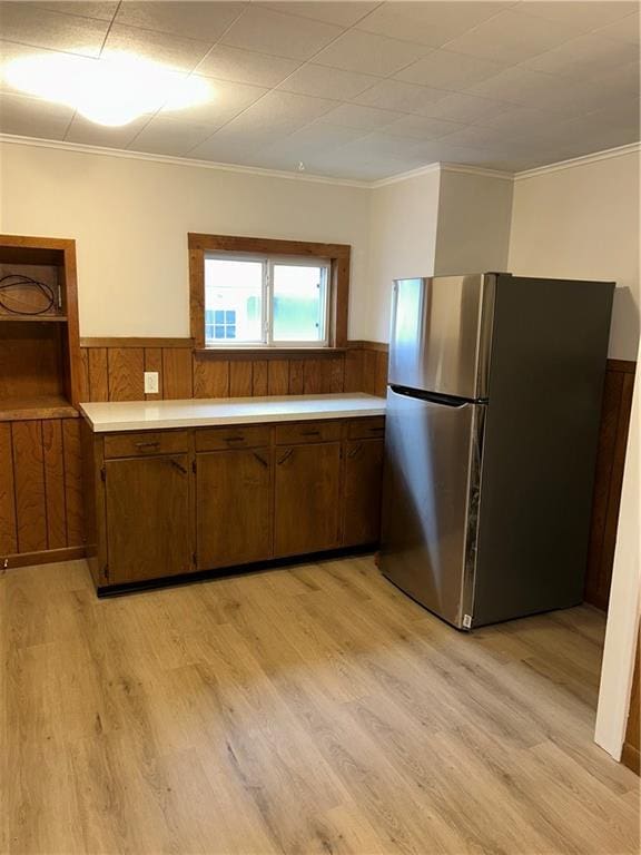 kitchen featuring stainless steel refrigerator, crown molding, and light hardwood / wood-style floors