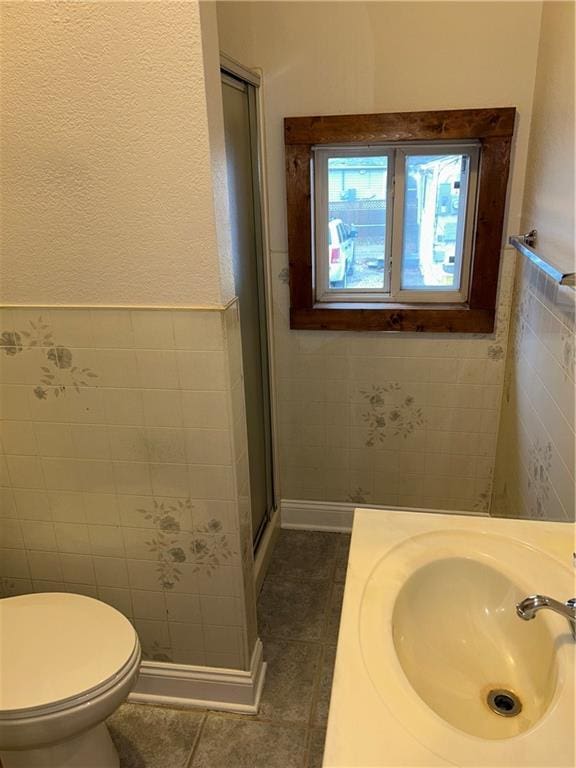 bathroom featuring vanity, tile patterned flooring, toilet, tile walls, and an enclosed shower