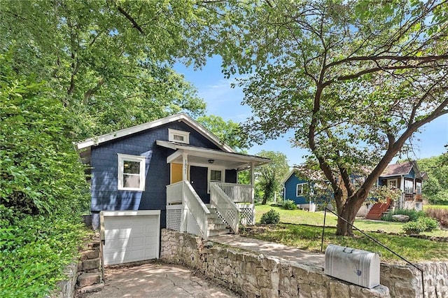 view of front of property with a porch, a garage, and a front lawn