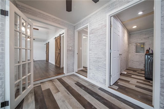 hall with a barn door, brick wall, and hardwood / wood-style flooring