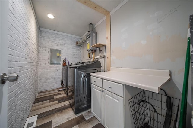 clothes washing area featuring independent washer and dryer, electric panel, dark wood-type flooring, and brick wall