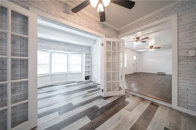 spare room with hardwood / wood-style floors, ceiling fan, french doors, and brick wall