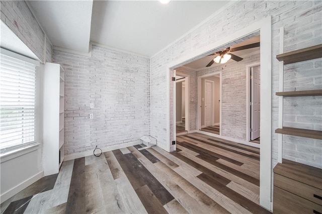 unfurnished room featuring ceiling fan, dark hardwood / wood-style flooring, and brick wall