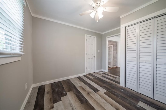 unfurnished bedroom featuring ceiling fan, dark hardwood / wood-style flooring, ornamental molding, and a closet