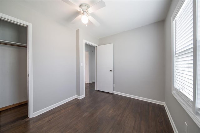 unfurnished bedroom with multiple windows, ceiling fan, a closet, and dark wood-type flooring