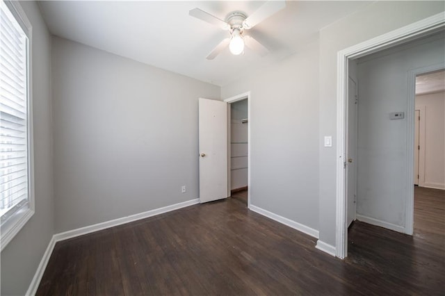 unfurnished bedroom featuring ceiling fan, a closet, dark wood-type flooring, and multiple windows