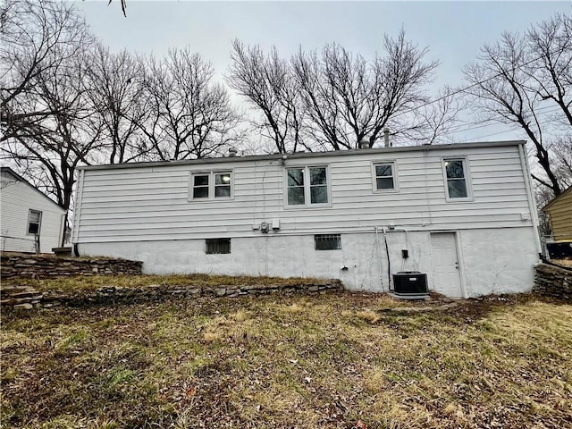 rear view of house with central AC unit and a yard