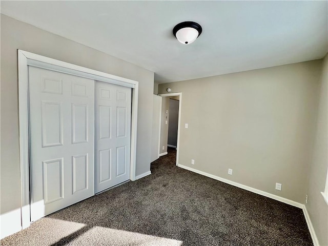 unfurnished bedroom featuring a closet and dark carpet