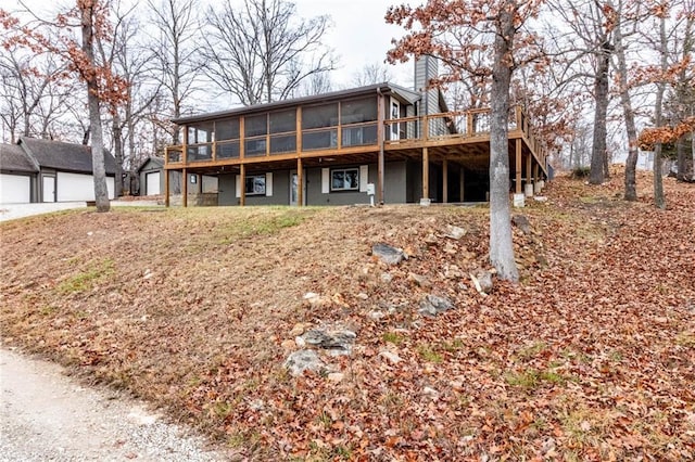 back of property with a sunroom and a deck