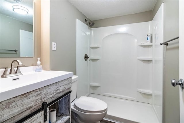 bathroom featuring toilet, vanity, and walk in shower