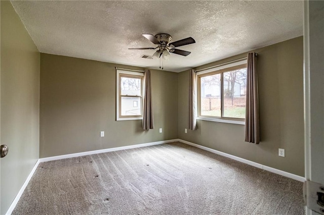 carpeted spare room with ceiling fan, a healthy amount of sunlight, and a textured ceiling