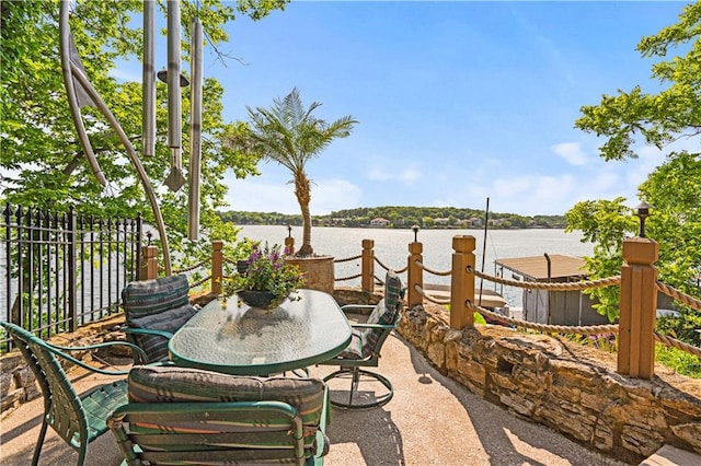 view of patio with a water view and fence