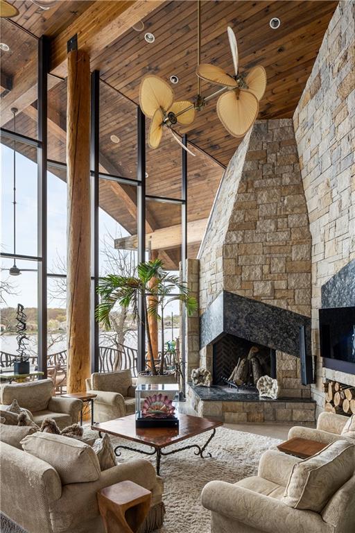 472 N Winnebago Dr, Lake Winnebago, MO 64034 - living area featuring wooden ceiling, a stone fireplace, a high ceiling, a ceiling fan, and a wall of windows