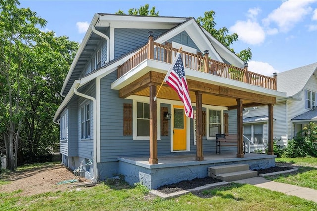 view of front facade with a balcony, covered porch, and a front yard