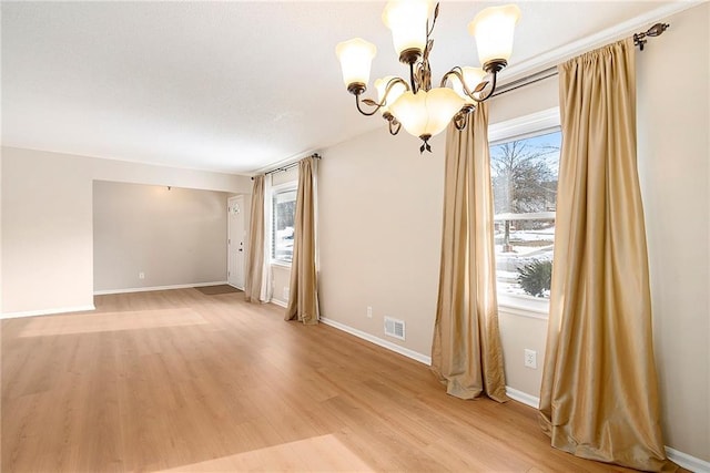 unfurnished room featuring hardwood / wood-style floors, a wealth of natural light, and a chandelier