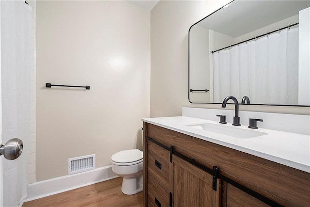 bathroom featuring vanity, hardwood / wood-style flooring, and toilet