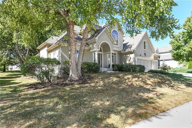 view of front of home featuring a garage, a front lawn, and stucco siding