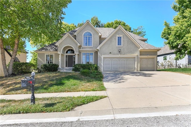 traditional home featuring an attached garage, a front lawn, concrete driveway, and stucco siding