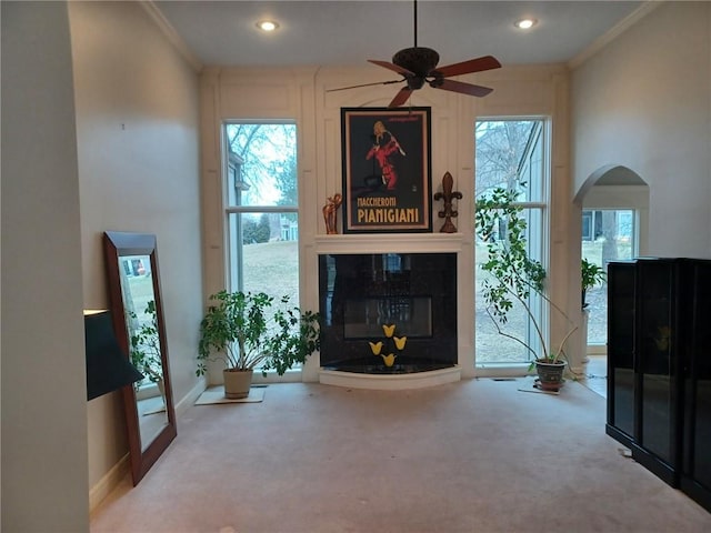 carpeted living area featuring ornamental molding, a glass covered fireplace, baseboards, and recessed lighting