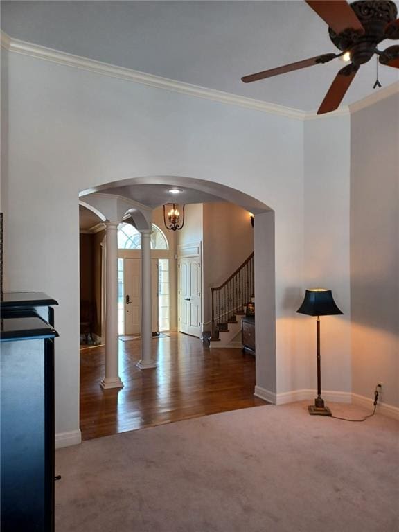 unfurnished living room featuring carpet floors, ornate columns, ornamental molding, and arched walkways